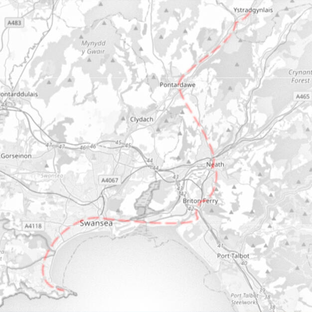 Map of the Line A black-and-white map of South Wales, covering areas including Ystradgynlais, Port Talbot, and Swansea. Various place names are given in text, and various mountain peaks are shown as triangles. The only colour in the image is a dashed red line, charting ou